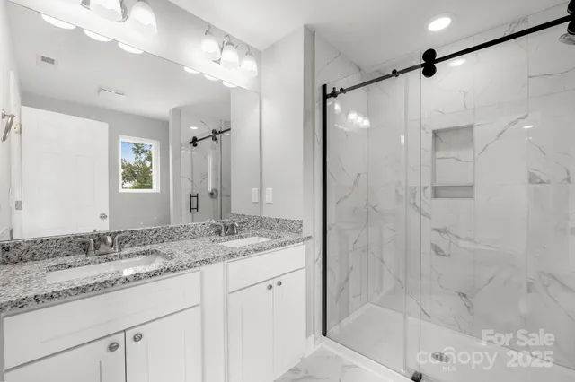 a bathroom with a granite countertop sink mirror and shower