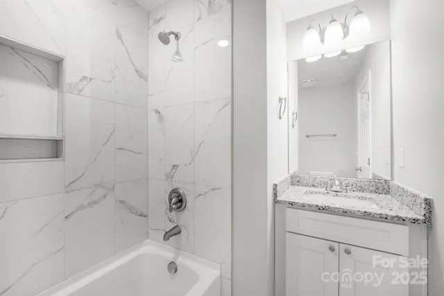 a bathroom with a granite countertop sink a mirror and a bathtub
