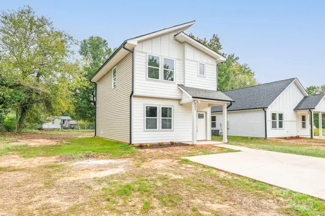 a view of a house with a yard and large tree