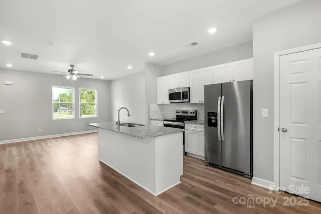 a kitchen with stainless steel appliances granite countertop a refrigerator and a stove top oven