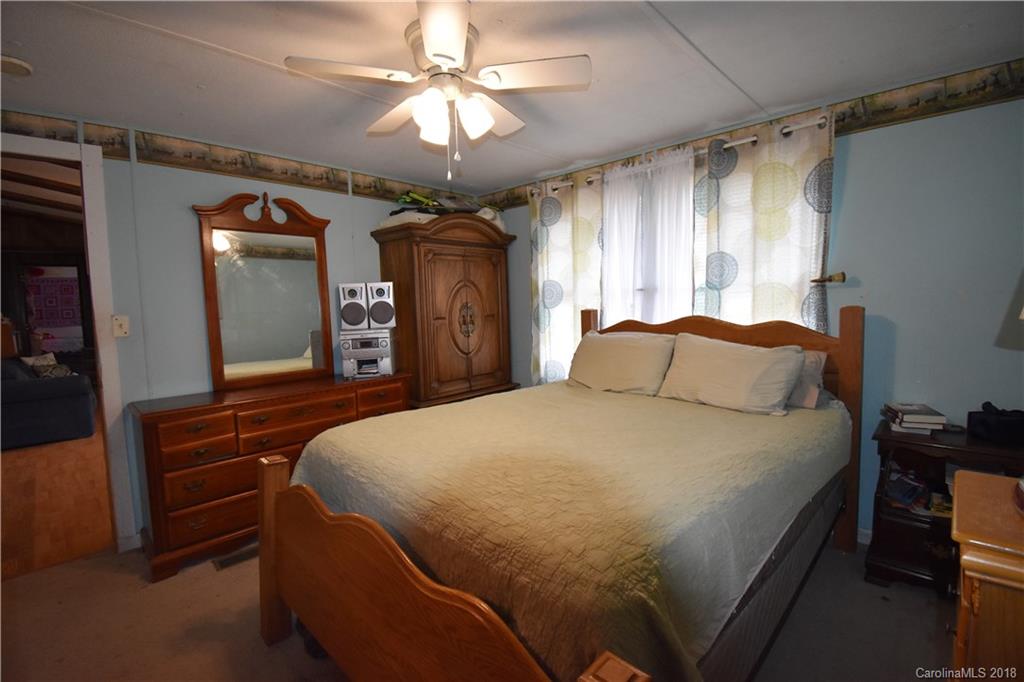 463 Lindsey Loop Road Fletcher, NC 28732 - Photo 19 of 27 a spacious bedroom with a large bed and a chandelier
