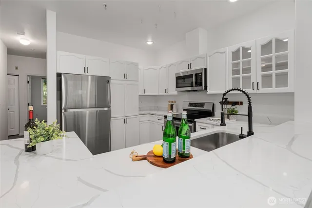 a kitchen with stainless steel appliances granite countertop a refrigerator a stove a sink a dining table and chairs