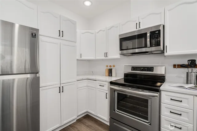 a kitchen with stainless steel appliances white cabinets white stove a microwave and a refrigerator