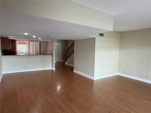 a view of a big room with wooden floor and a kitchen