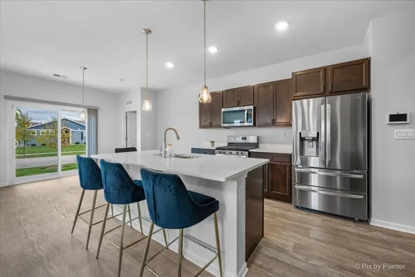 a kitchen with stainless steel appliances a sink a stove a refrigerator and island with wooden floor