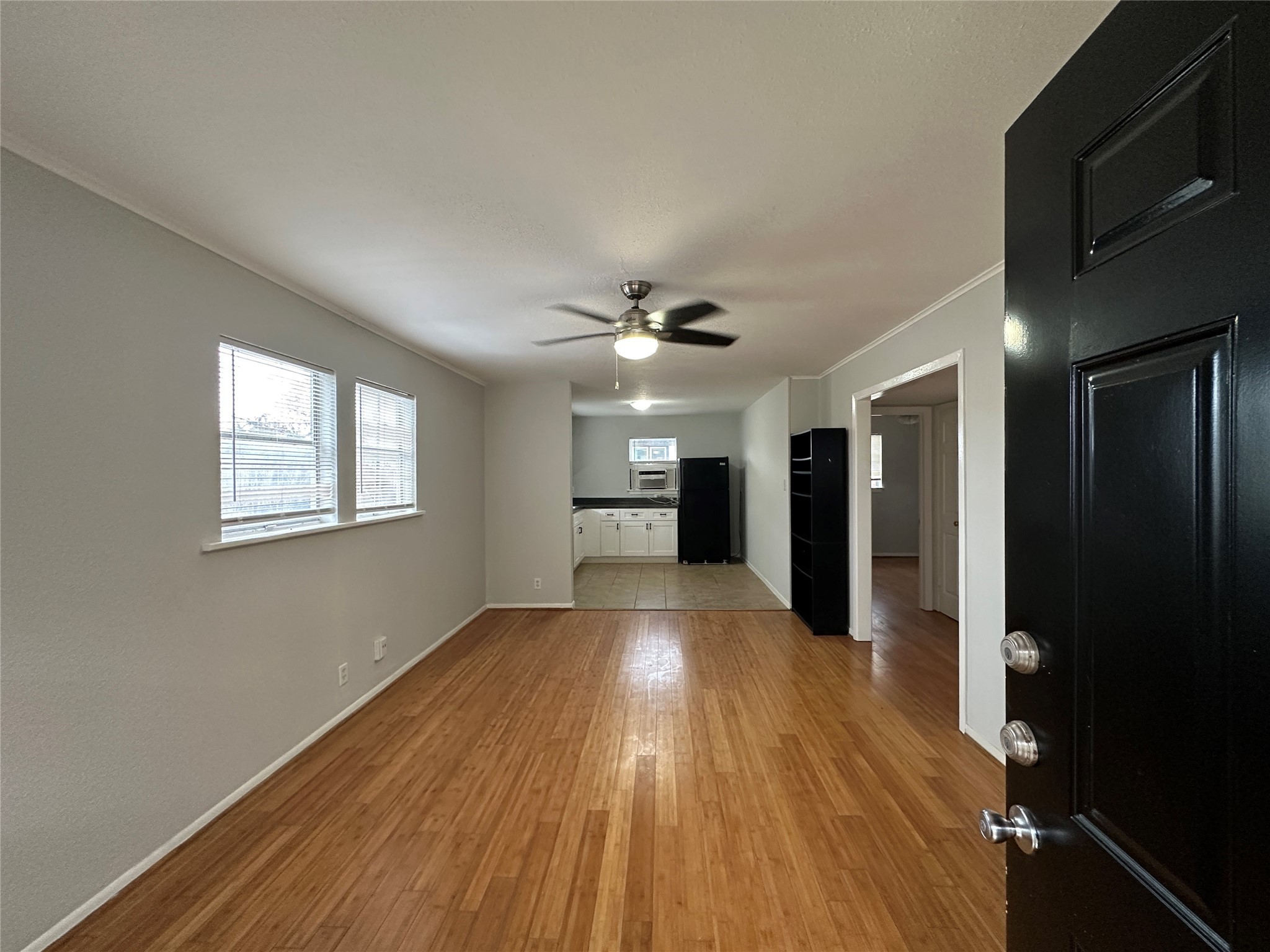 a view of a big room with wooden floor a ceiling fan and windows