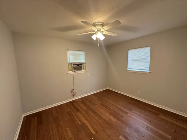 a view of a room with wooden floor and a ceiling fan