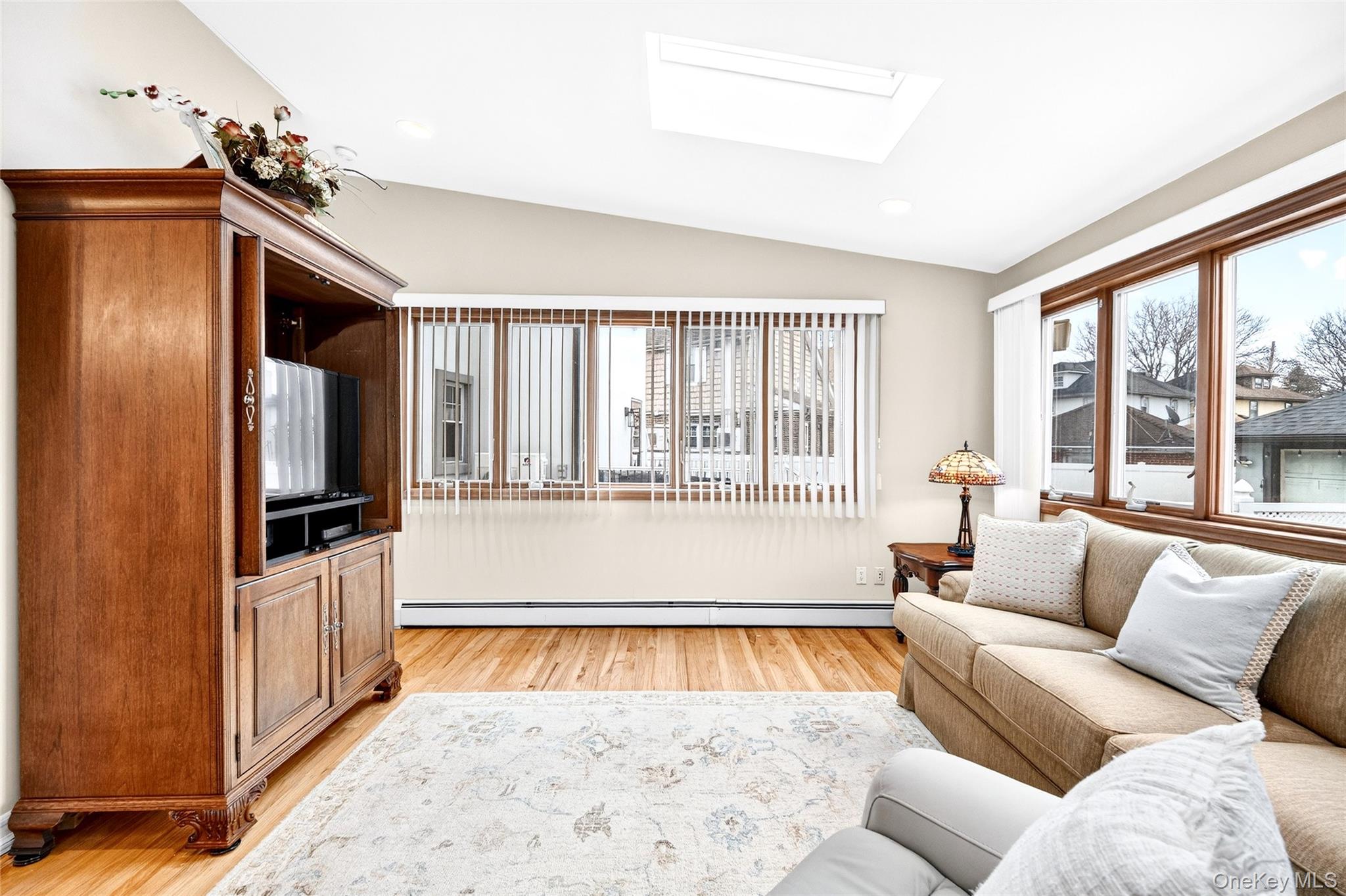 3334 Country Club Road Bronx, NY 10465 - Photo 22 of 49 Living room featuring vaulted ceiling, light wood-type flooring, a skylight, a baseboard heating unit, and recessed lighting