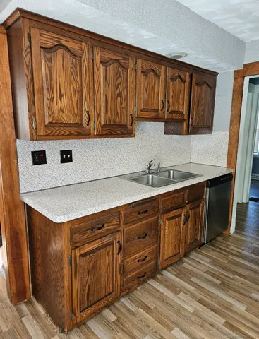 a kitchen with stainless steel appliances granite countertop a sink dishwasher stove and cabinets with wooden floor