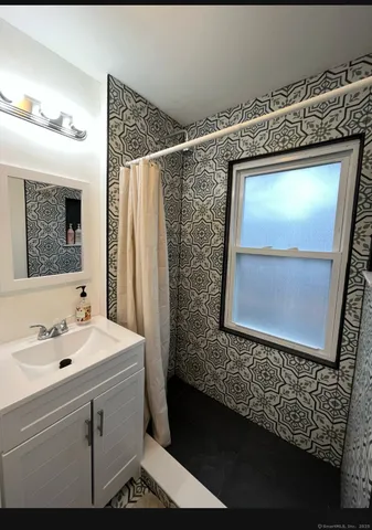 a bathroom with a sink and mirror with bathtub