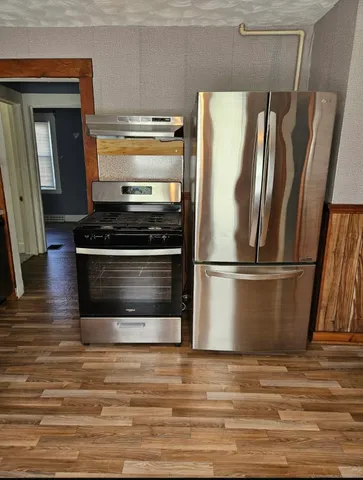 a view of a kitchen with wooden floors and stainless steel appliances