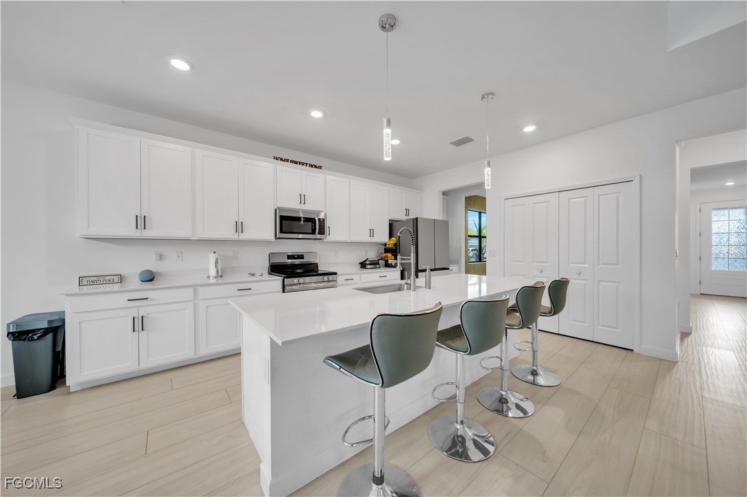11264 Canopy Loop Fort Myers, FL 33913 - Photo 14 of 49 a kitchen with stainless steel appliances granite countertop a sink a stove a refrigerator cabinets and chairs