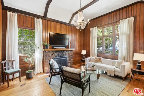 a living room with furniture large window and wooden floor