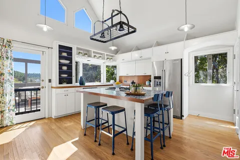 a kitchen with stainless steel appliances a stove center island a dining table and chairs