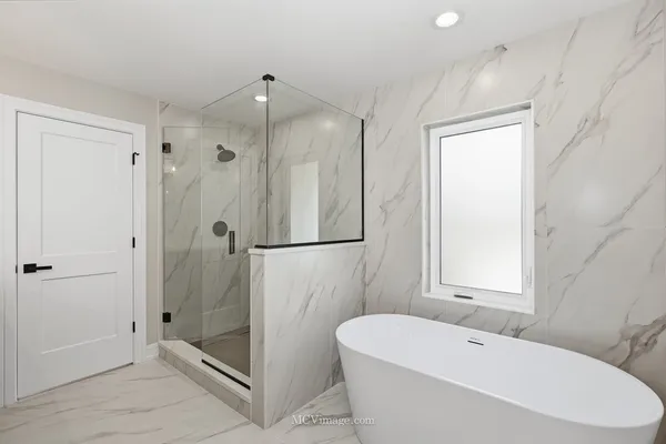 a bathroom with a white bath tub a shower and a sink