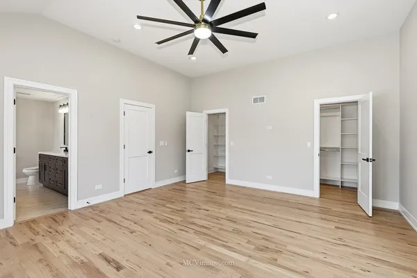 a view of a livingroom with a chandelier fan and wooden floor