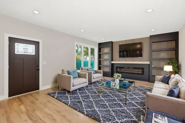 a living room with furniture a fireplace a flat screen tv and windows