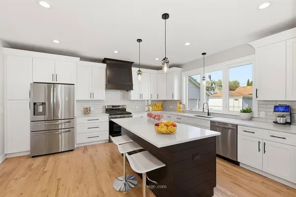 a kitchen with a refrigerator a stove a sink and white cabinets with wooden floor