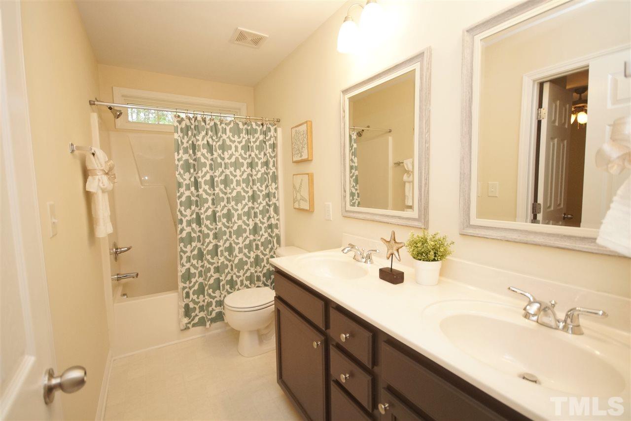 5209 Groveside Court Raleigh, NC 27613 - Photo 22 of 25 a bathroom with a shower sink vanity mirror and toilet