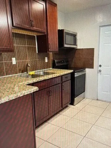 a kitchen with stainless steel appliances granite countertop a stove a sink and a microwave