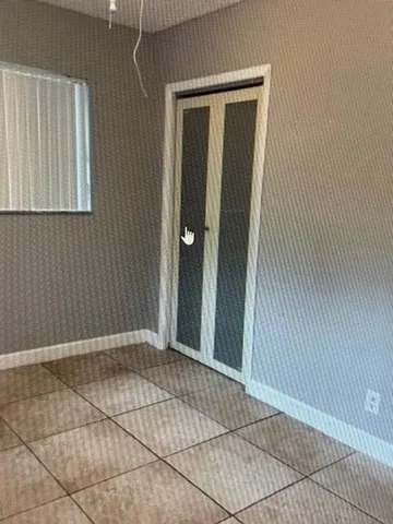a view of an empty room with cabinet and a window