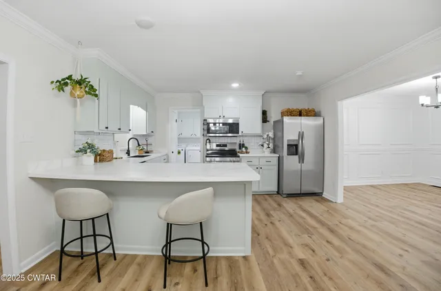 a kitchen with stainless steel appliances a dining table chairs refrigerator and sink