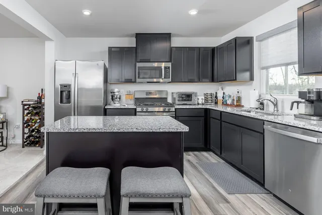 a kitchen with stainless steel appliances granite countertop a sink a stove a refrigerator and a cabinets