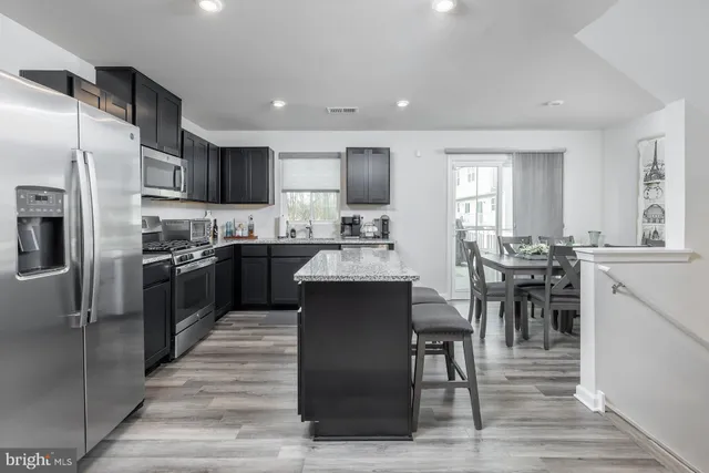 a kitchen with stainless steel appliances granite countertop a table chairs sink refrigerator and cabinets