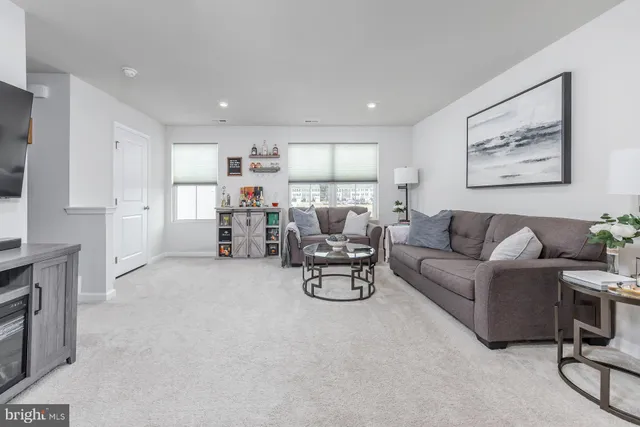 a living room with furniture and a dining table with kitchen appliances