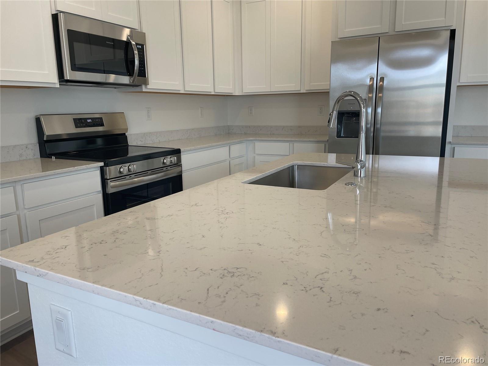 12883 Range Street Firestone, CO 80504 - Photo 4 of 39 a kitchen with stainless steel appliances a refrigerator a stove a microwave and cabinets