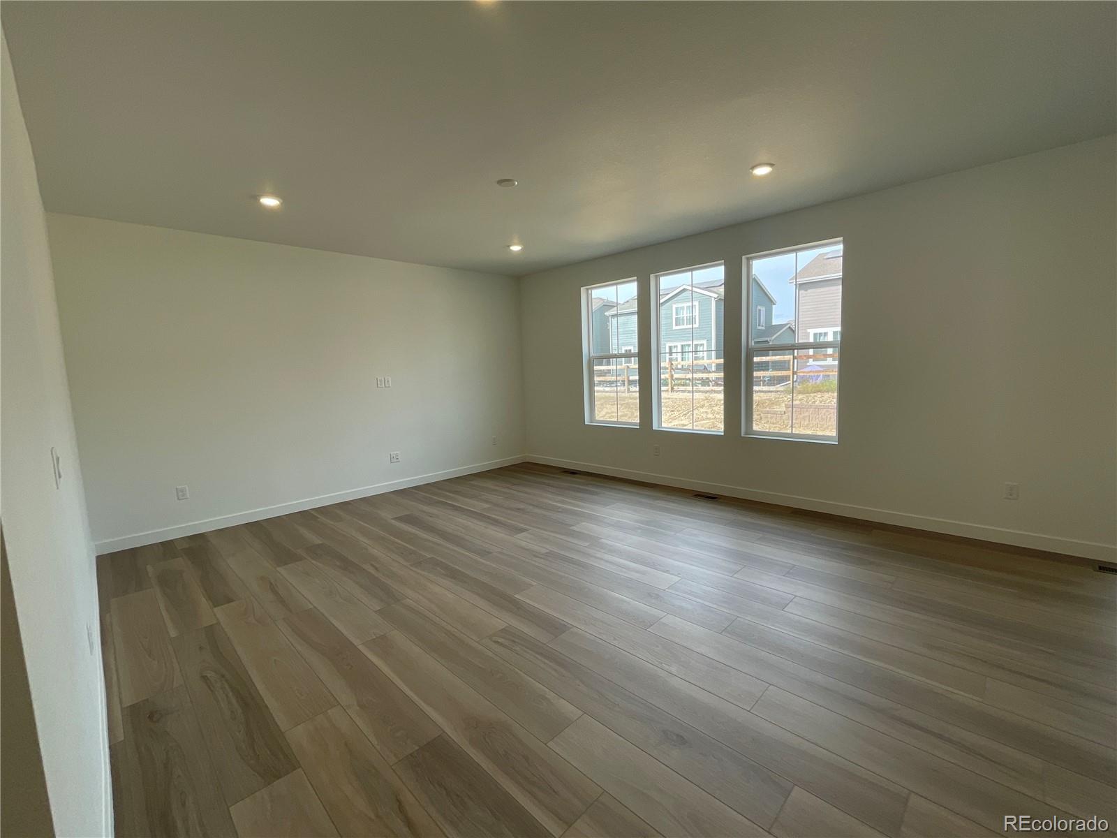 12883 Range Street Firestone, CO 80504 - Photo 5 of 39 an empty room with wooden floor and windows