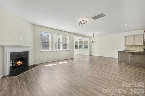 a view of an empty room with wooden floor fireplace and a window