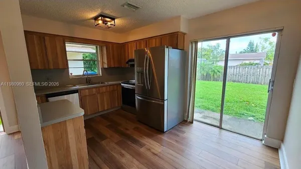 a kitchen with stainless steel appliances granite countertop a refrigerator a sink a stove a washer dryer and white cabinets