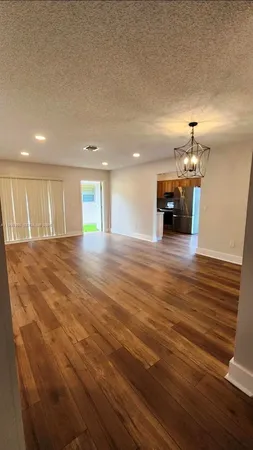 an empty room with wooden floor and chandelier