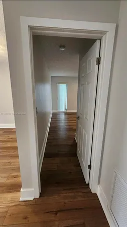 a view of a hallway to a hallway with wooden floor and staircase
