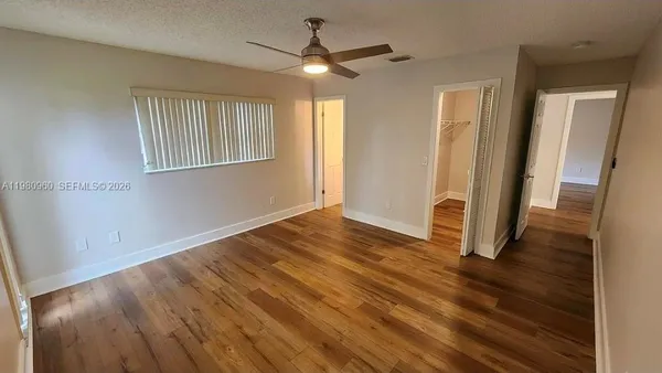 an empty room with wooden floor and a ceiling fan