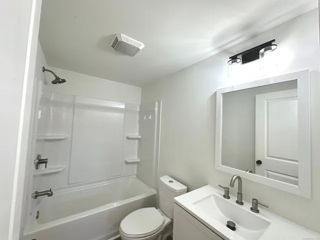a bathroom with a bathtub shower sink vanity and toilet