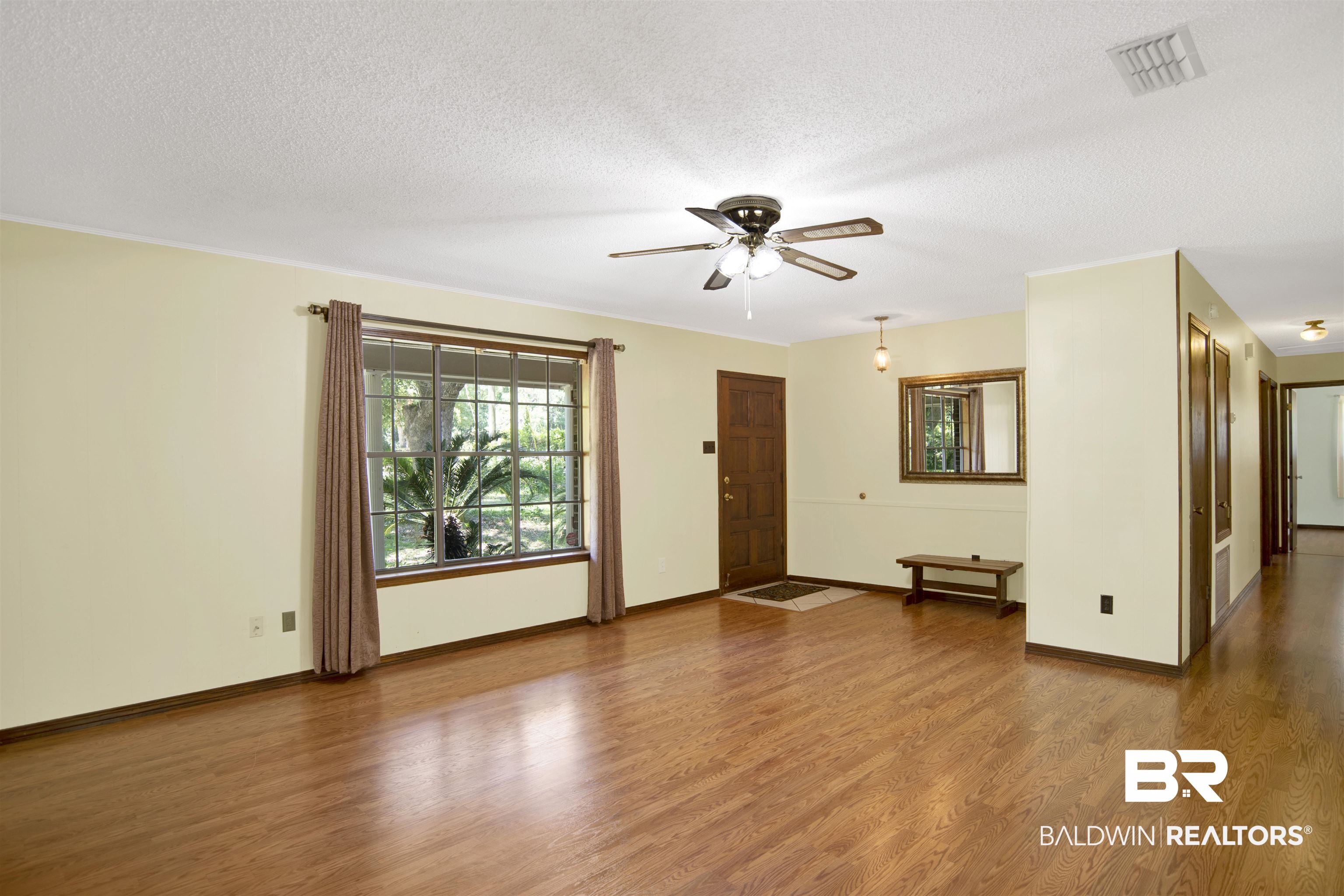 30888 Cemetery Road Daphne, AL 36527 - Photo 12 of 36 Spacious interior featuring wood-finish flooring, a prominent window with exterior greenery, and a ceiling fan