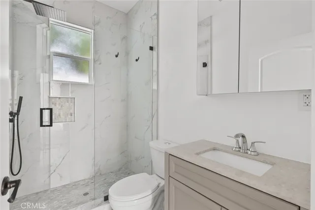 a bathroom with a granite countertop sink a toilet and shower