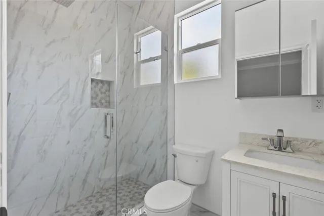 a bathroom with a granite countertop sink toilet a mirror and shower