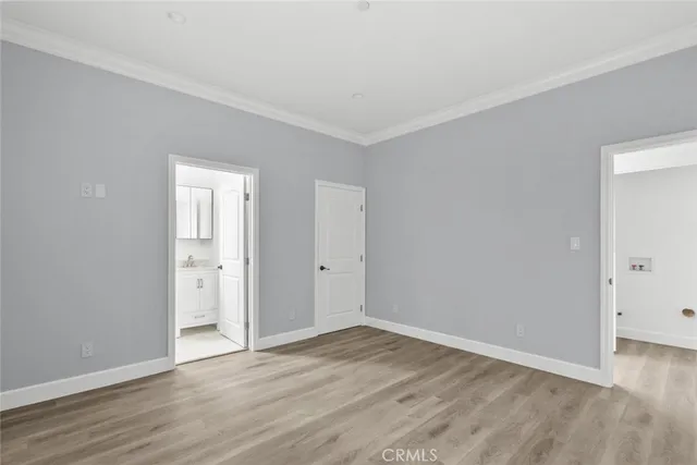 a view of an empty room with wooden floor and closet