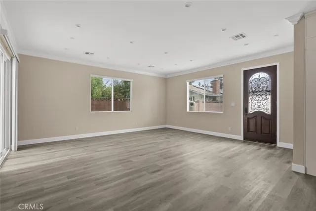 a view of an empty room with a window and wooden floor