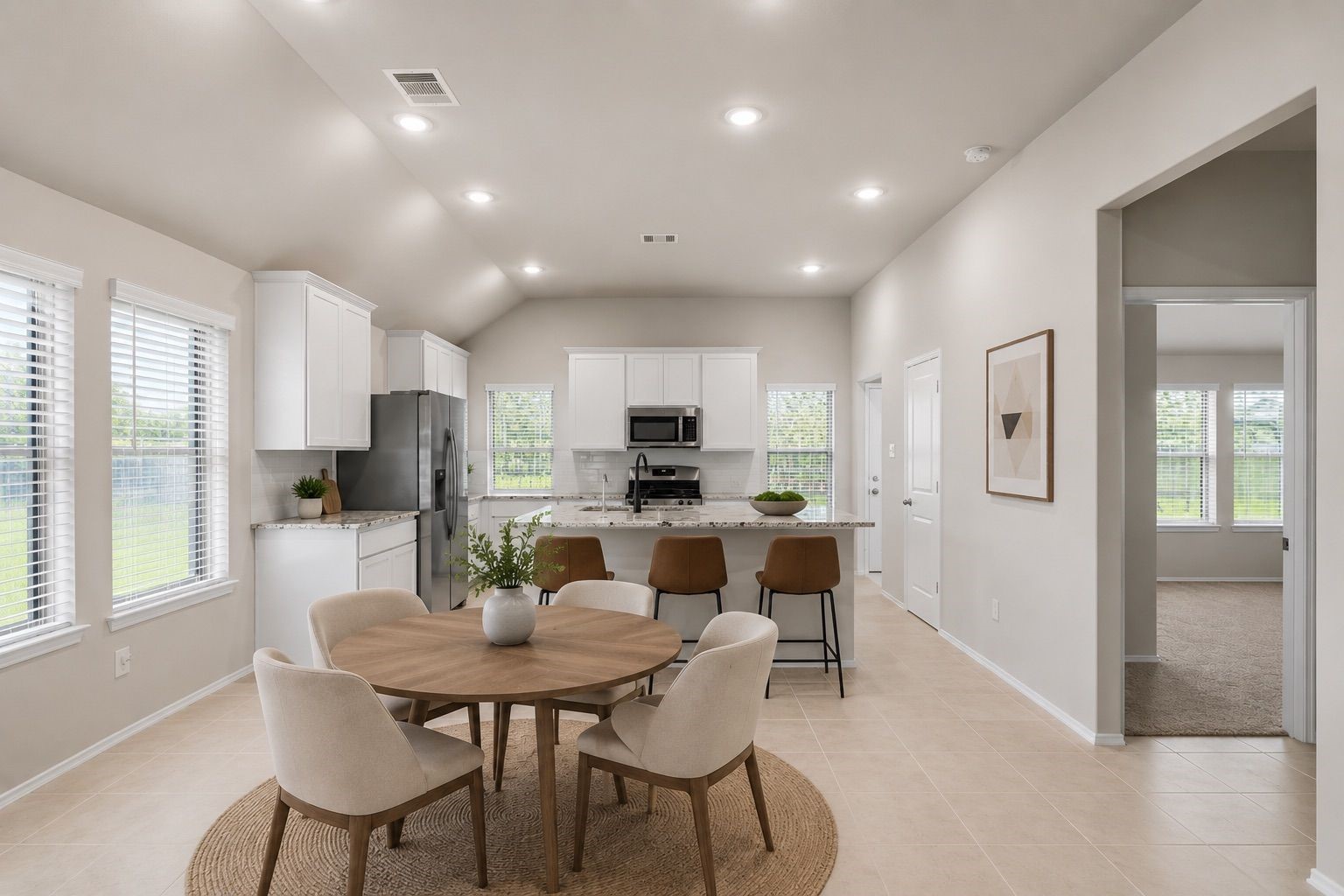 2011 Oak Leaf Court Manvel, TX 77578 - Photo 10 of 28 Bright, modern kitchen with white cabinetry, a spacious island with bar stools, and an adjacent dining area. Large windows provide ample natural light, and there's an open connection to a living space. The neutral tones create a welcoming atmosphere.