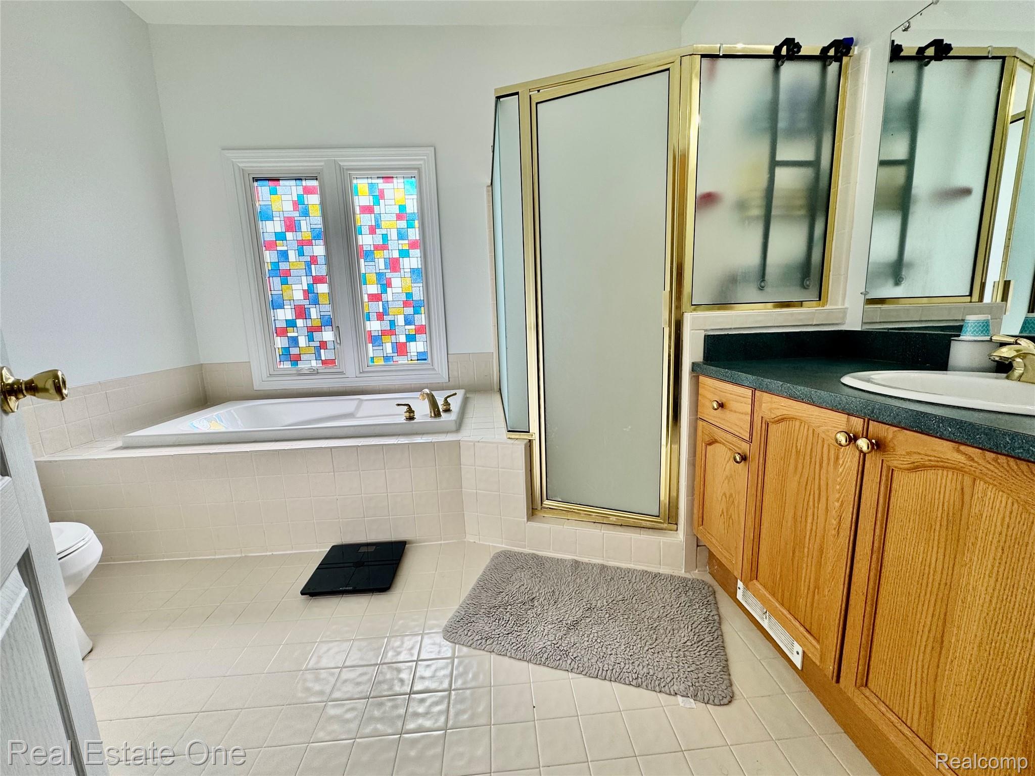 1668 South Shore Drive Rochester, MI 48307 - Photo 15 of 27 Full bath featuring light tile patterned flooring, a bath, a shower stall, and vanity