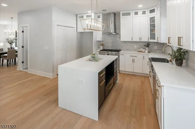 a view of kitchen with stainless steel appliances wooden floor dining table and chairs