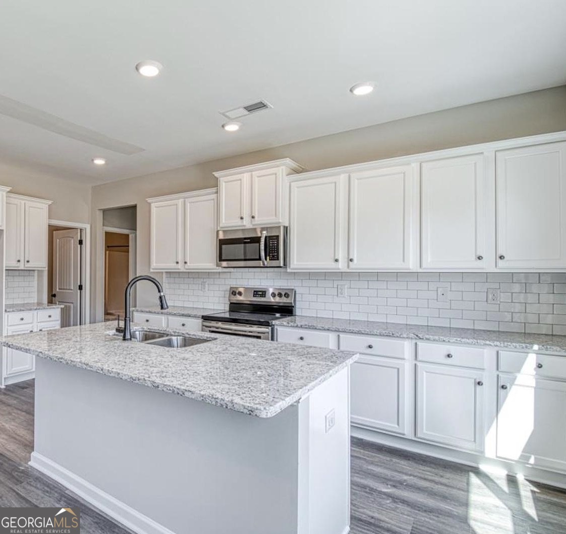 1172 Faulkner Way Jonesboro, GA 30238 - Photo 7 of 9 a kitchen with kitchen island granite countertop a sink white cabinets and stainless steel appliances