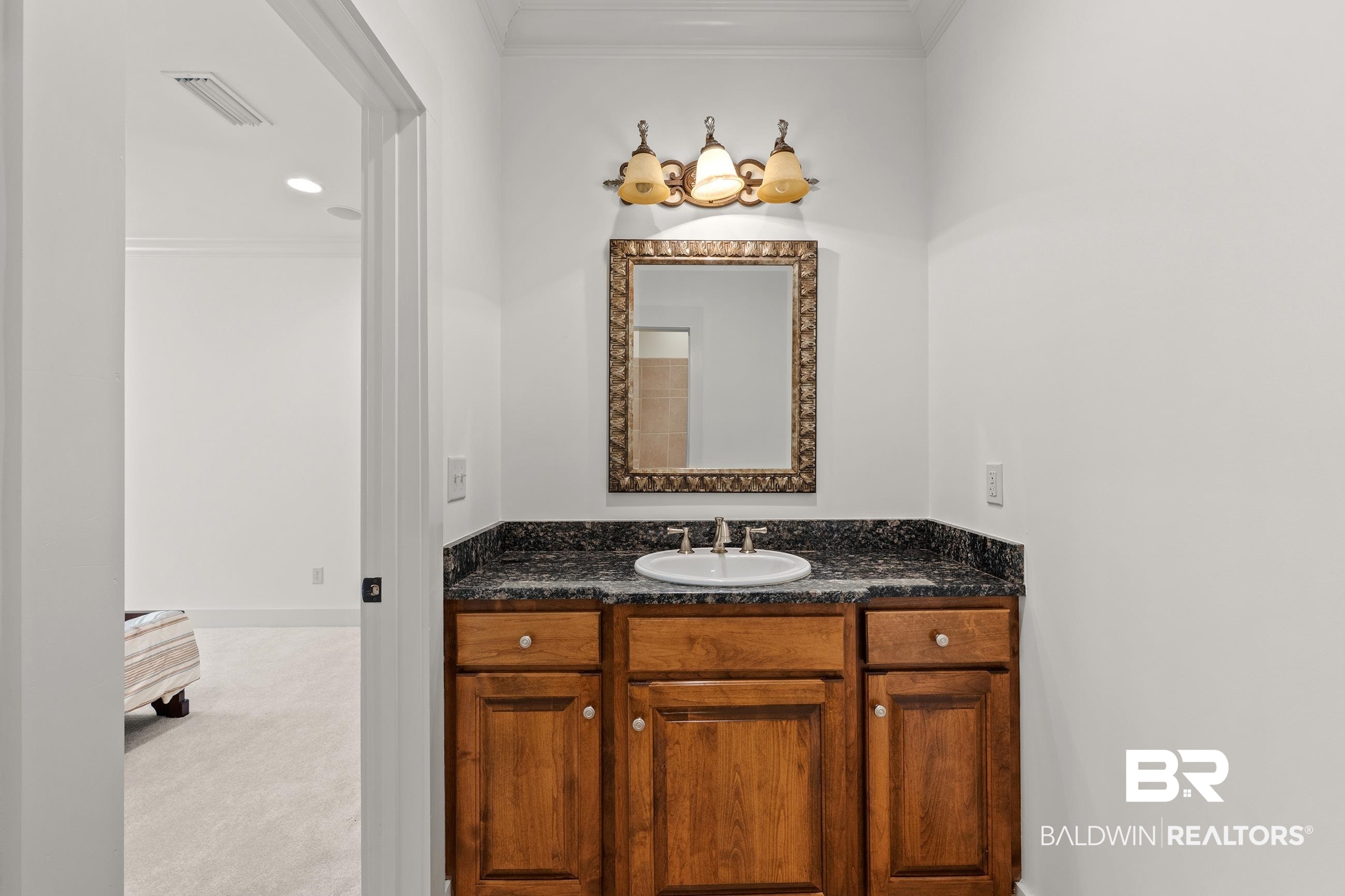 30463 Dolive Ridge Daphne, AL 36527 - Photo 51 of 58 Wood-finish vanity with a drop-in sink, dark speckled countertop, and ornate framed mirror