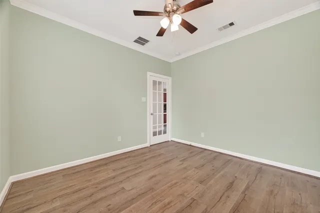 an empty room with wooden floor ceiling fan and windows