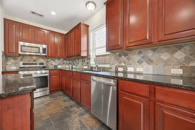 a kitchen with stainless steel appliances granite countertop wooden cabinets a sink and dishwasher