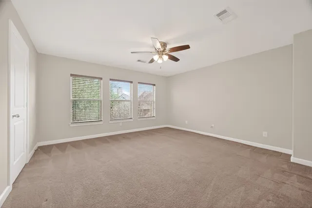 an empty room with chandelier fan and windows